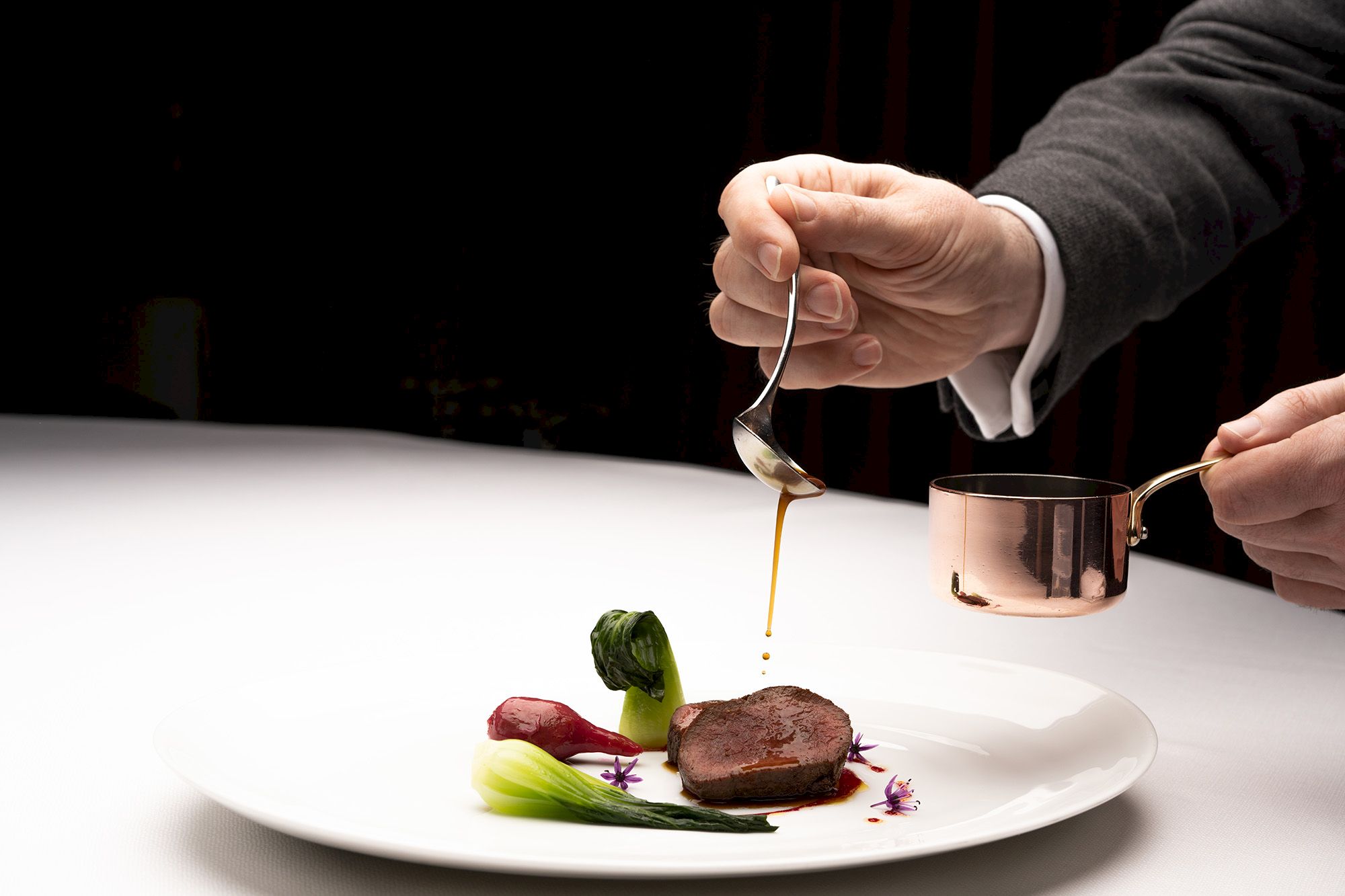 Plate of delicious food with sauce being poured over